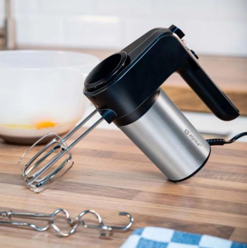 Ein stilvoller Handmixer aus Edelstahl und Kunststoff mit Rührbesen auf einer Holzarbeitsplatte, daneben eine Schüssel mit Eiern.