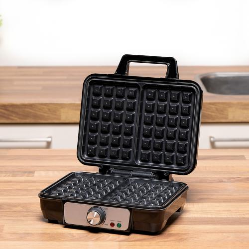 Ein Waffeleisen auf einer Arbeitsplatte in der Küche, offen mit zwei antihaftbeschichteten Waffelplatten.